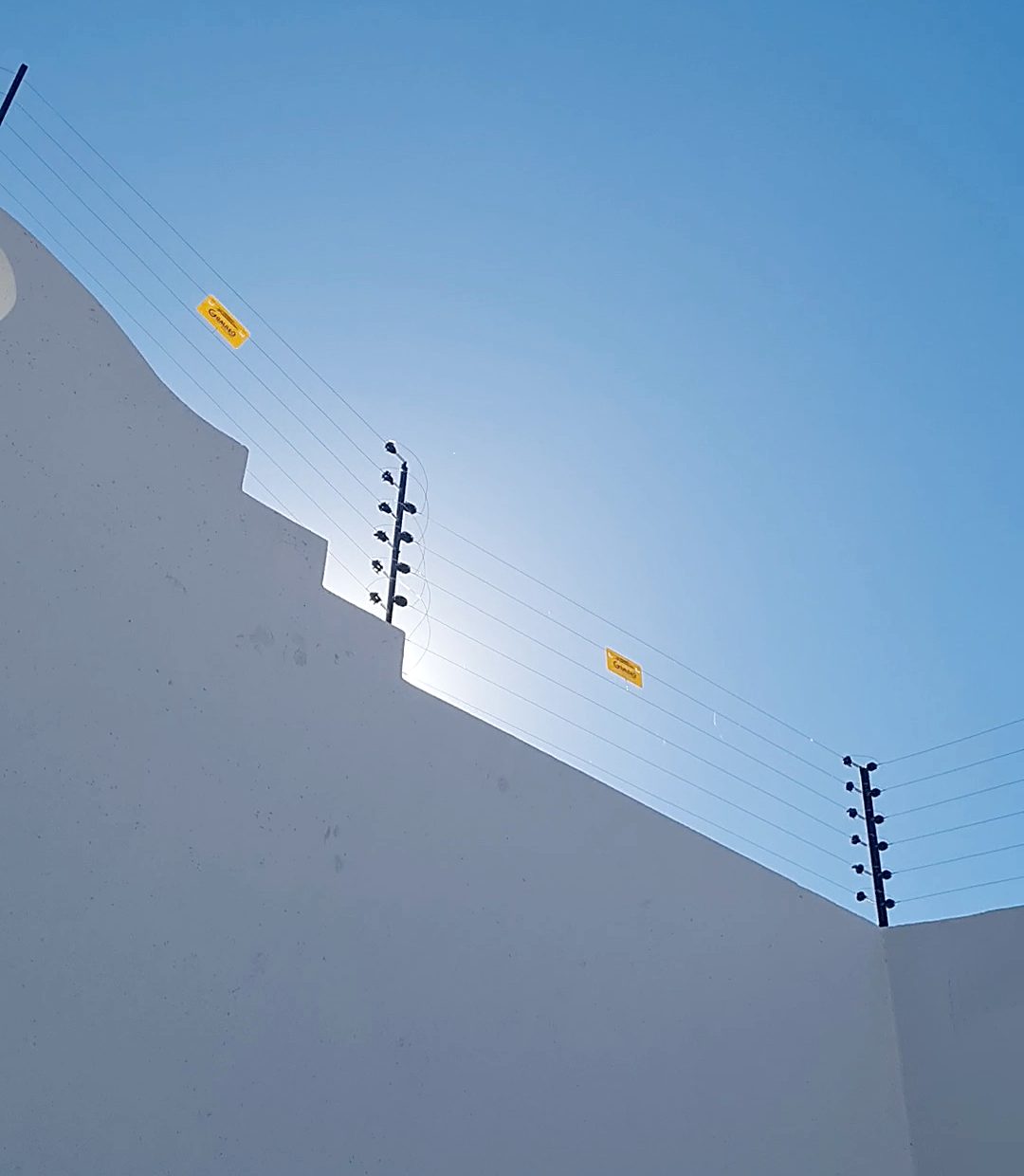 Cerco eléctrico sobre muro perimetral blanco escalonado